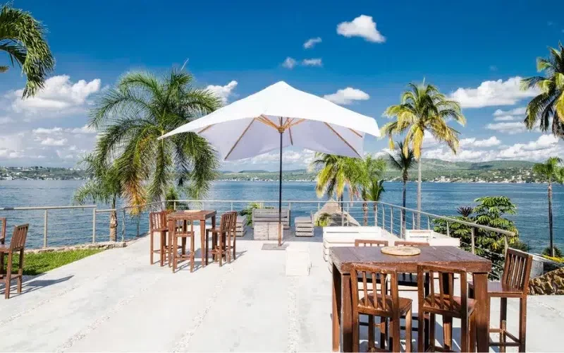 Terraza con mesas y palapas en el complejo Tres Cielos. Al fondo se encuentra el lago de Tequesquitengo