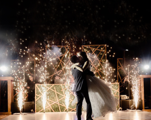Novios abrazados celebrando su boda en un jardin de Morelos. Al fondo espectáculo de fuegos artificiales.
