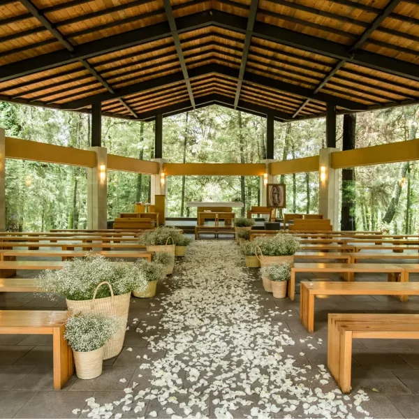 Imagen panorámica de salón de eventos y bodas. Se observa el mobiliario con mesas, sillas y decoración natural.