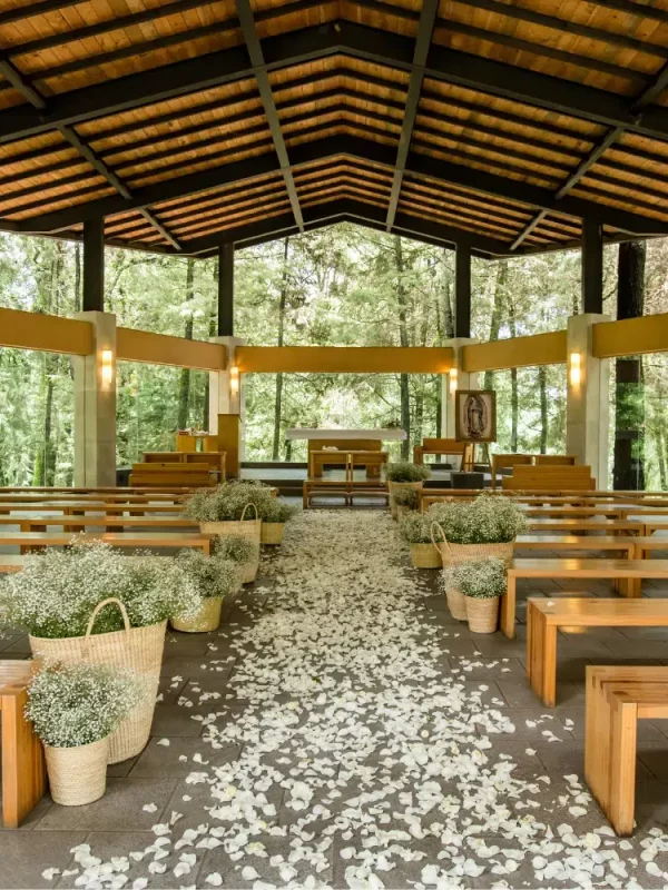 Imagen panorámica de salón de eventos y bodas. Se observa el mobiliario con mesas, sillas y decoración natural.